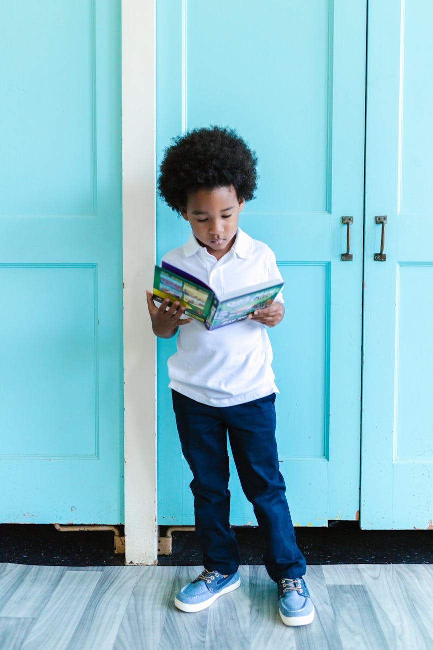 a cute boy standing while reading a book