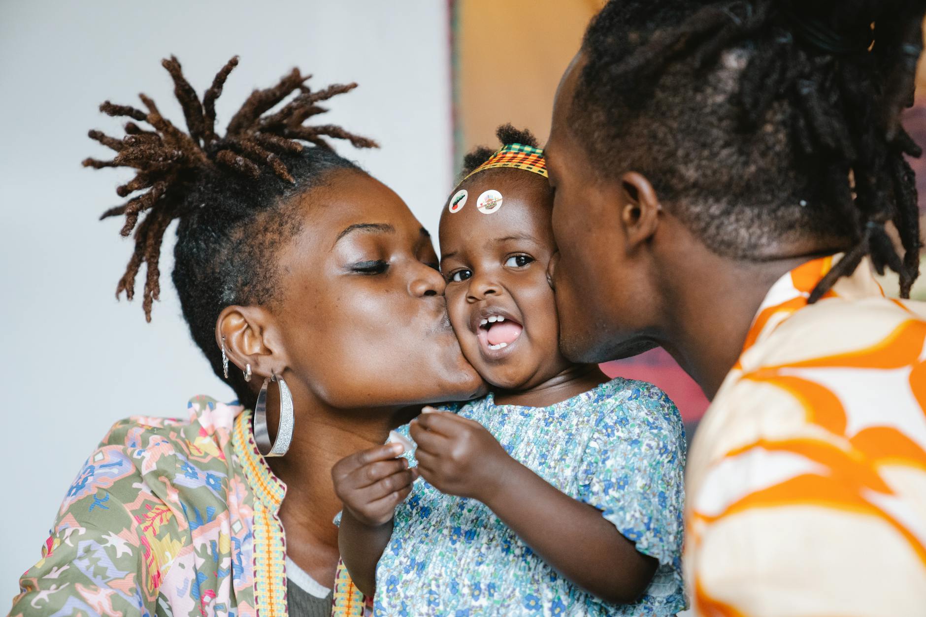 a couple kissing their cute daughter